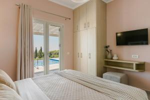 a bedroom with a bed and a tv and a pool at Saint Nicholas Villas 5 in Skala +52 photos