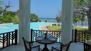 a table on a balcony with a view of a pool at Zahari Oceanfront in Msambweni +16 photos