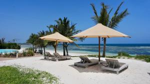 a group of chairs and umbrellas on a beach at Zahari Oceanfront in Msambweni