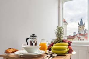 a table topped with a plate of fruit and juice at Celine Prague Luxury Hostel in Prague