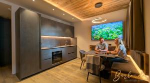 two people sitting at a table in a kitchen at Isolden Green Srl Berlanda Mountain suites in Cavalese