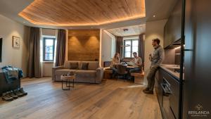 a man standing in a kitchen with two people in a living room at Isolden Green Srl Berlanda Mountain suites in Cavalese