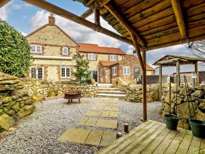 a house with a stone wall and a wooden patio at 5 Bed in Leeds oc-91355 in Sherburn in Elmet