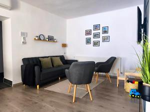 a living room with a black couch and two chairs at GRAND HOME Apartman in Sárospatak