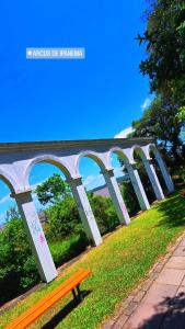 a bench sitting in the grass under a bridge at Carcará Hostel Ipanema - Zona Sul POA in Porto Alegre