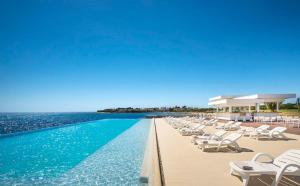 a swimming pool with lounge chairs and the ocean at Apartments Agata in Novigrad Istria