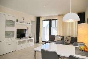 a white living room with a couch and a tv at Haus Titania App 6 inkl WLAN in Grömitz
