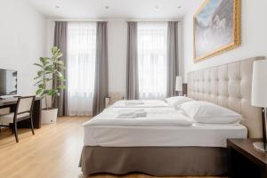 a bedroom with a large white bed and a desk at Riverside Palace Apartments in Prague