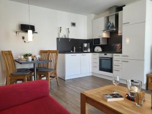 a kitchen with white cabinets and a table with a red couch at Ferienwohnung "Strandläufer 1" in Böhl