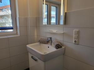 a white bathroom with a sink and a mirror at Ferienwohnung "Strandläufer 1" in Böhl +12 photos