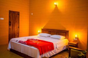 a bedroom with a bed with a red blanket on it at Walawa Wild Place in Udawalawe