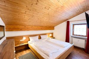 a bed in a room with a wooden ceiling at Ferienwohnung Forggensee-Blick in Schwangau