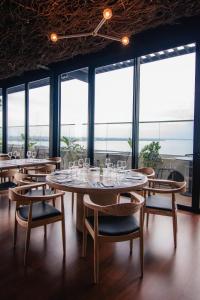 a dining room with tables and chairs and large windows at Alula Hotel Encarnacion in Encarnación