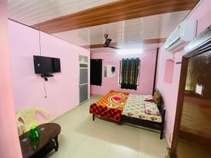 a pink room with a bed and a tv at Arbuda inn in Mount Ābu