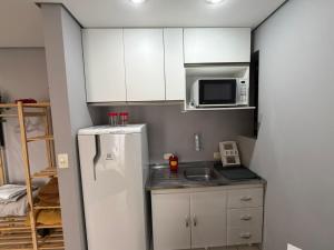 a small kitchen with white cabinets and a refrigerator at Hotel Flat Biena Parque Ibirapuera 1101 incluso estacionamento in São Paulo