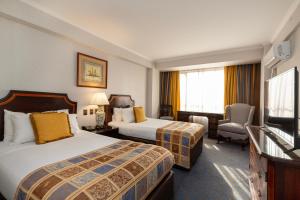 a hotel room with two beds and a flat screen tv at Park Plaza Santiago in Santiago