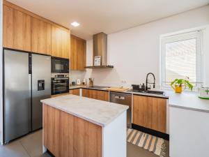 a kitchen with wooden cabinets and a stainless steel refrigerator at Casa Mar in Cortegaça +14 photos