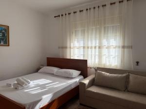 a bedroom with a bed and a couch and a window at Rent rooms Loren in Vlorë