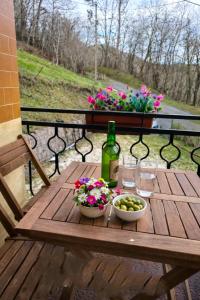a wooden table with a bottle of wine and flowers at Casa las granxias in El Escobal
