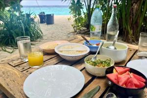 a wooden table with plates of food on the beach at Privates Strandhaus auf den Malediven in Kudafari