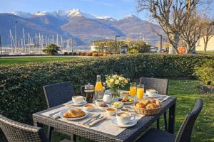 a table with breakfast food on it with mountains in the background at Villa Lago Groundfloor Lakefront Beach Garden Bike&Boat& Scooter Lake Como in Colico