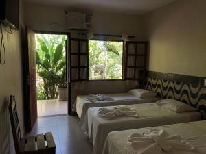 two beds in a room with a window and a room with two beds sidx sidx at Virgínia Palace in Corumbá +40 photos