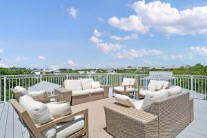 a patio with wicker chairs and chairs on a balcony at 80 Blue Sky in Santa Rosa Beach