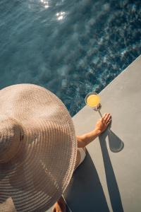 a person holding a wine glass next to a pool at West East Suites in Imerovigli