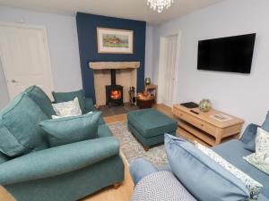 a living room with blue furniture and a fireplace at Linn Cottage in Hexham