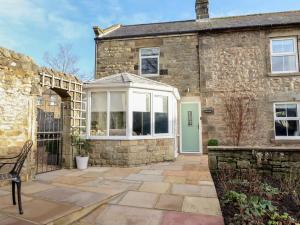 an exterior view of a stone house with a conservatory at Linn Cottage in Hexham