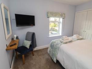 a bedroom with a bed and a chair and a television at Linn Cottage in Hexham