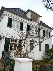 a white house with green shuttered windows at Peaceful Apartment-3 Zi, Loggia & Garden in Blankenese in Hamburg
