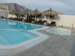 a pool at a resort with chairs and umbrellas at Perissa Design Centro Suites- BEACH FRONT in Perissa