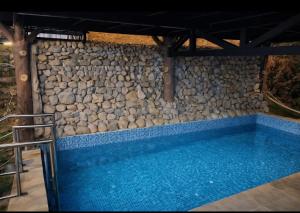 a swimming pool with a stone wall next to a rock wall at River and Roots Resort, Riverside Boutique Stay , Bonfire, Scenic Views in Dehradun
