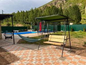 a hammock with a canopy next to a pool at Bardzunq Garden Resort in Goghtʼ