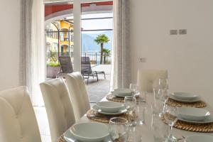 a dining room with a table with white chairs and a view of a patio at Elegant Lake View Apartment with Pool in Lavena Ponte Tresa