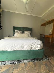 a bed with a green headboard in a bedroom at Unit 7-9 at Homely Escapes in Phalaborwa