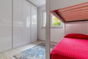 a bedroom with a red bed and a window at Elegant Lake View Apartment with Pool in Lavena Ponte Tresa