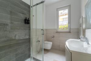 a bathroom with a shower and a toilet and a sink at Elegant Lake View Apartment with Pool in Lavena Ponte Tresa +17 photos