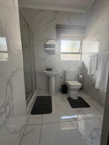 a white bathroom with a sink and a toilet at Unit 7-9 at Homely Escapes in Phalaborwa