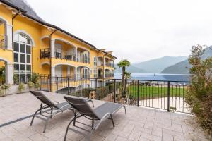 a patio with two chairs and a yellow building at Elegant Lake View Apartment with Pool in Lavena Ponte Tresa