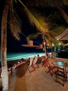 a group of people sitting in chairs on the beach at night at Pousada Villa Mar Porto in Porto De Galinhas