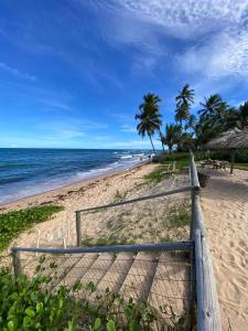 a wooden fence on a beach with the ocean at Pousada Farol das Tartarugas in Praia do Forte