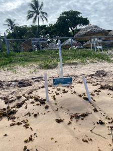 a sign in the sand on a beach at Pousada Farol das Tartarugas in Praia do Forte