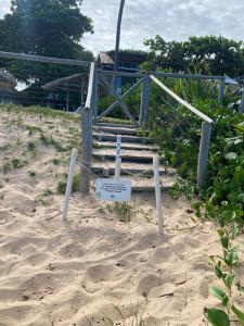 a sign in the sand in front of a beach at Pousada Farol das Tartarugas in Praia do Forte
