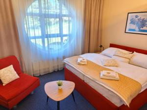 a hotel room with a bed and a red chair at Wellness Hotel Staré Město in Uherské Hradiště