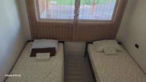 two beds in a small room with a window at Donde Dubon Pandi house in Puerto Jiménez +4 photos