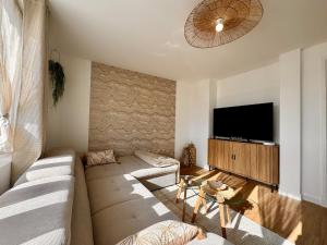 a living room with a couch and a flat screen tv at Le Nid Doré in Calais