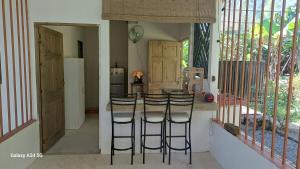 a kitchen with a counter with bar stools and a refrigerator at Donde Dubon Pandi house in Puerto Jiménez