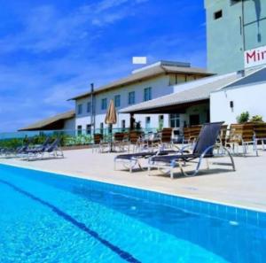a swimming pool with chairs and a hotel at Hotel Mirante São Brás in São Brás do Suaçuí